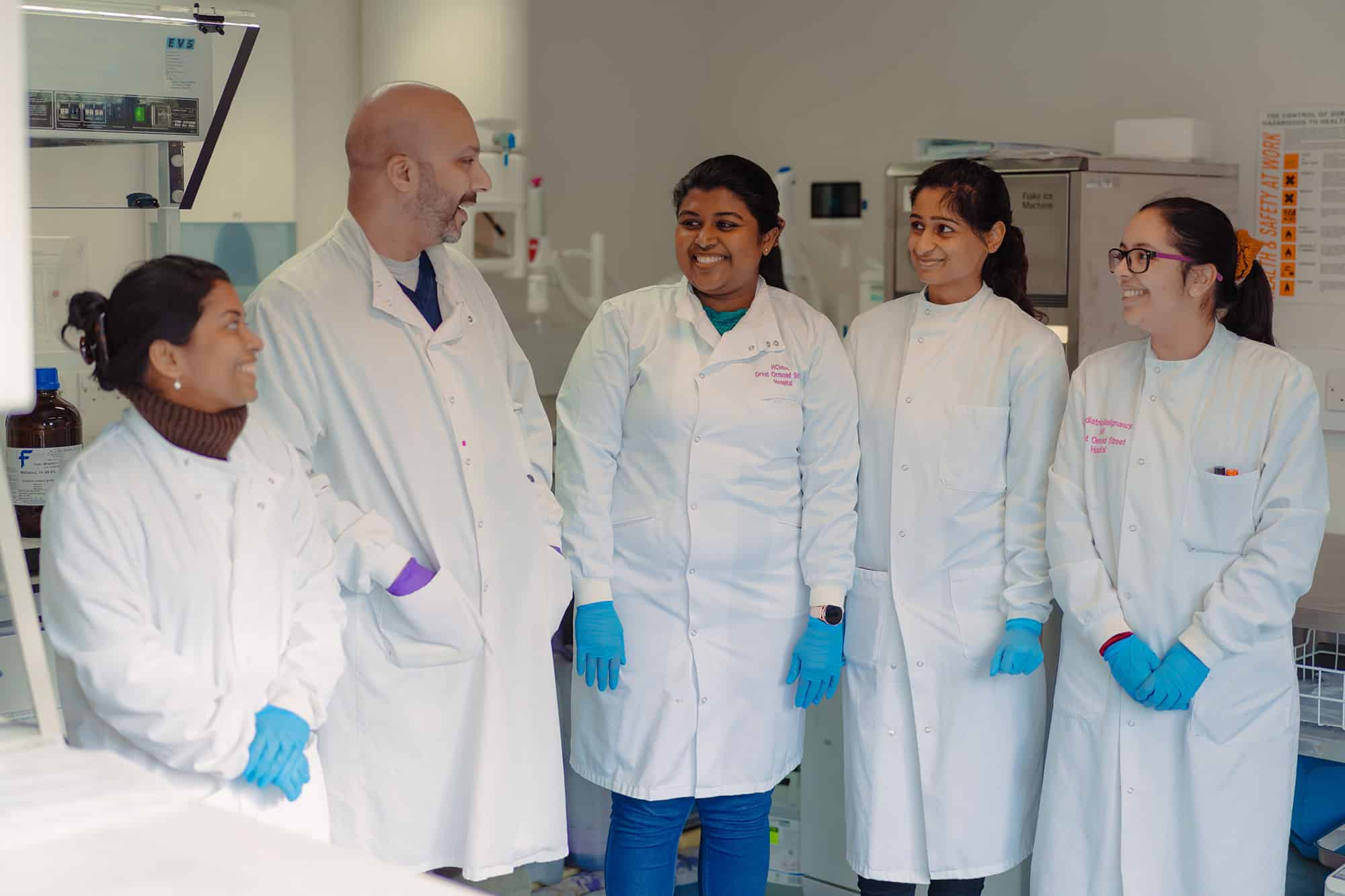 five scientists in PPE talking in a lab