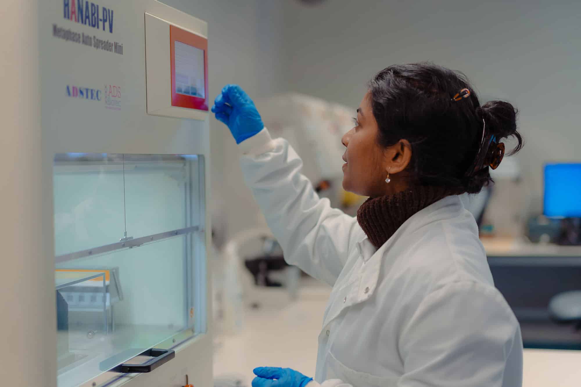 A woman in lab coat using a machine